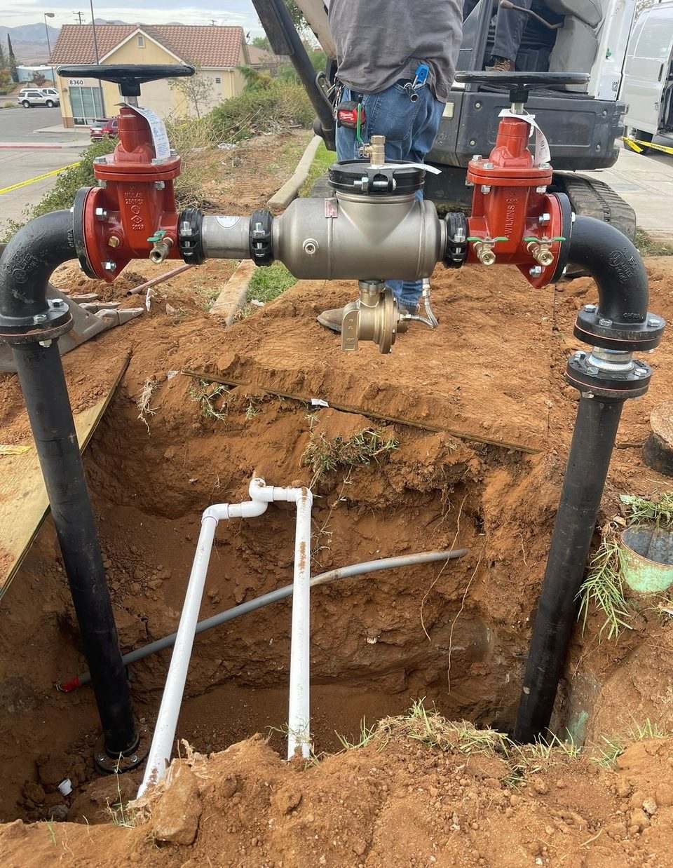 Large commercial backflow prevention assembly with red gate valves being set on a new water service line