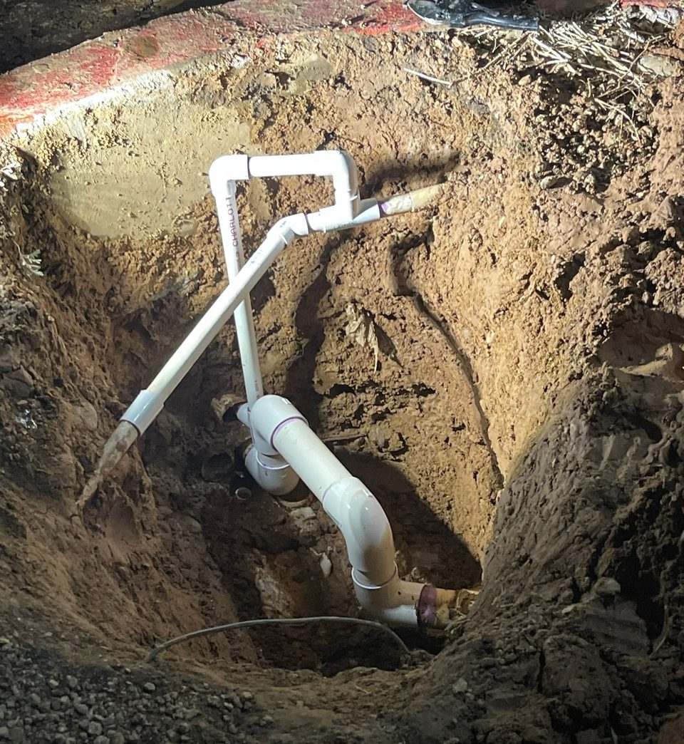 New white PVC sewer piping assembled at the bottom of a deep excavation